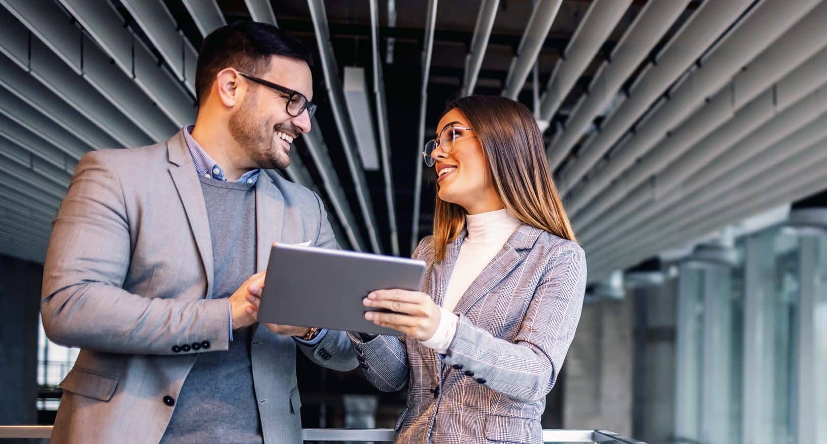 Business people meet in a commercial office setting discussing over a tablet computer.